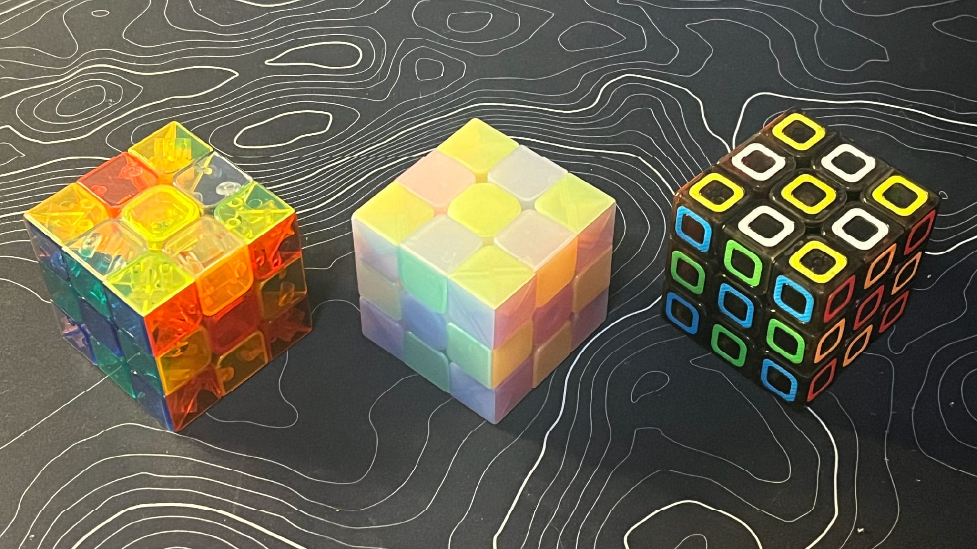 A transparent YJ Yulong, a Jelly Qiyi Warrior W, and a QiYi Dimensions 3x3.