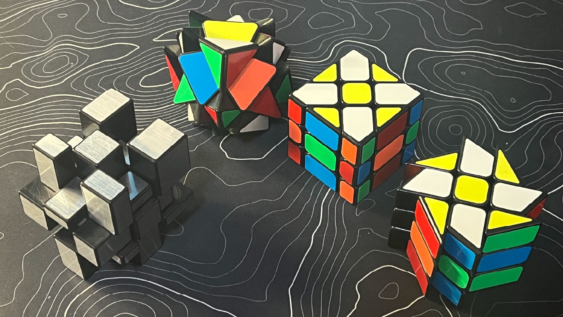 A ShengShou Mirror Blocks, YJ Axis Cube V2, YJ Fisher Cube V2, and YJ Windmill Cube V2, all in a checkerboard pattern.