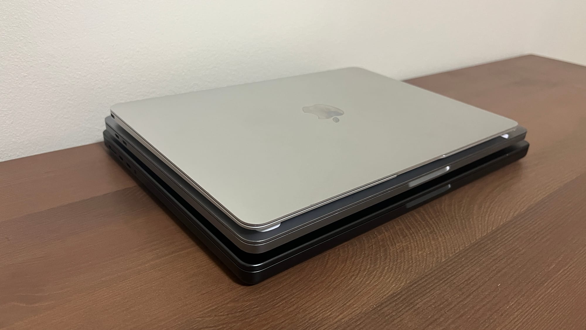 The Silver 2015 12-inch MacBook, on top of a space gray 2020 13-inch MacBook Pro, on top of a space black M4 14-inch MacBook Pro.