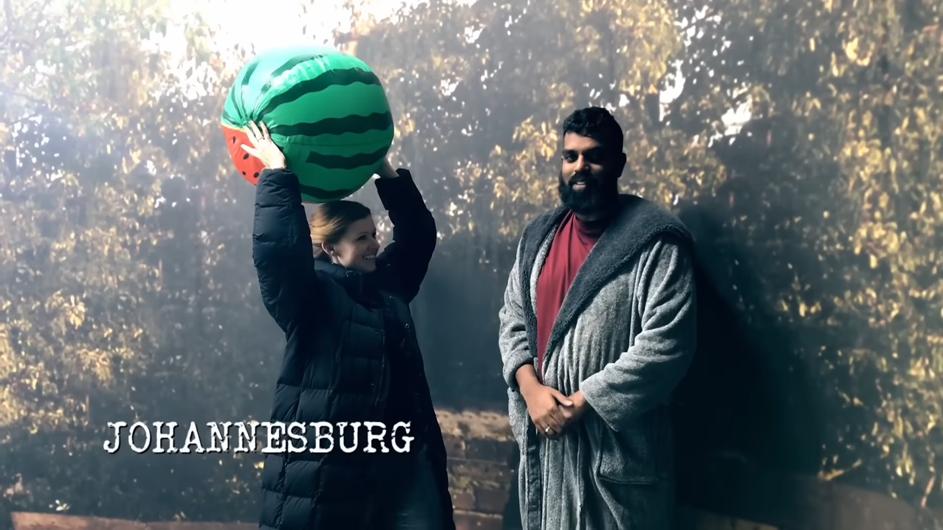 Sian Gibson holding a giant watermelon beach ball next to Romesh Ranganathan. They claim to be in Johannesburg.