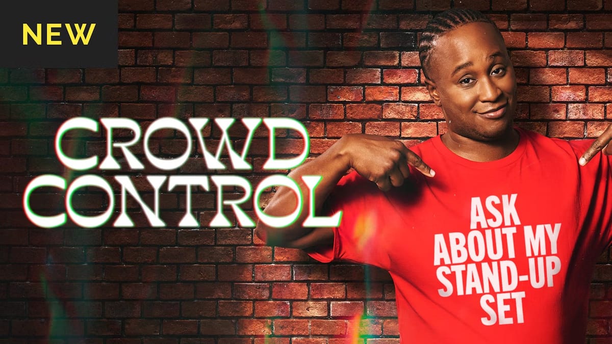 The cover for Crowd Control in dropout.tv. Host Jacquis Neal is pointing at his red shirt saying "Ask about my stand-up set" in front of a brick background.