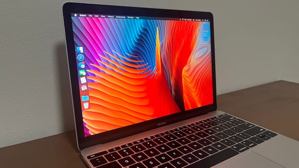 My Silver 2015 12-inch Retina MacBook. The screen is on with the Abstract Shapes wallpaper.